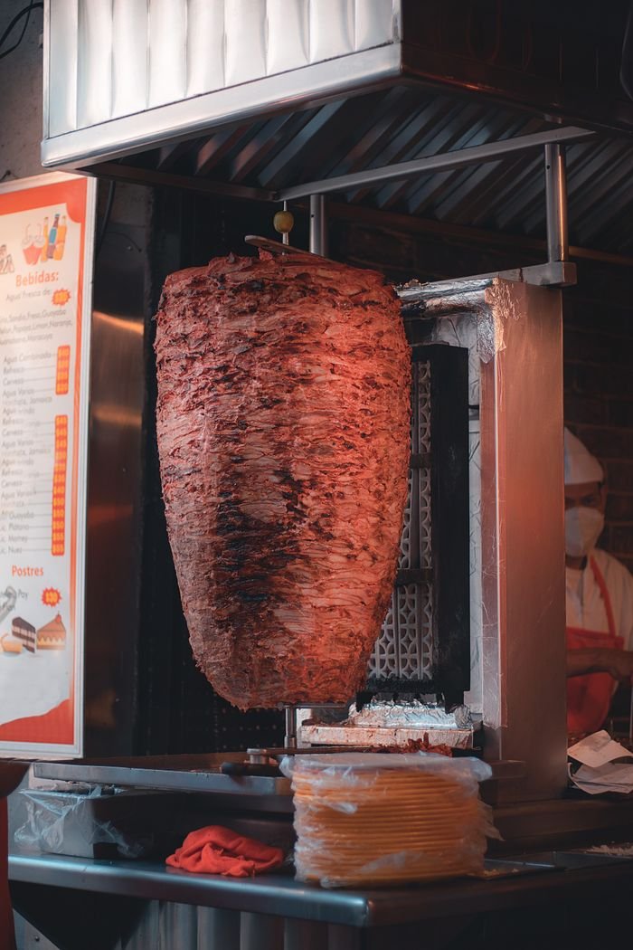 Home Delicious shawarma rotating on a vertical grill at a street food restaurant.